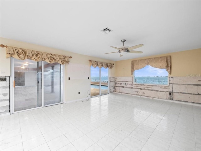 empty room with ceiling fan and a water view