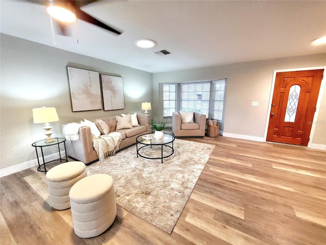 living area featuring light wood-style floors, visible vents, and baseboards