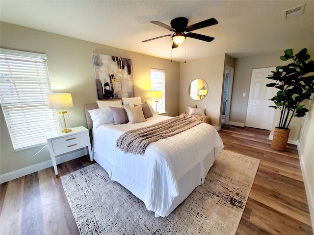 bedroom with baseboards, visible vents, and wood finished floors