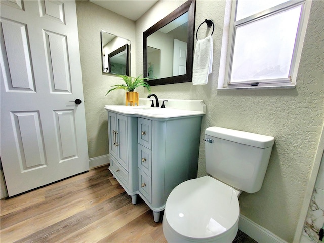 bathroom with a textured wall, vanity, toilet, and wood finished floors