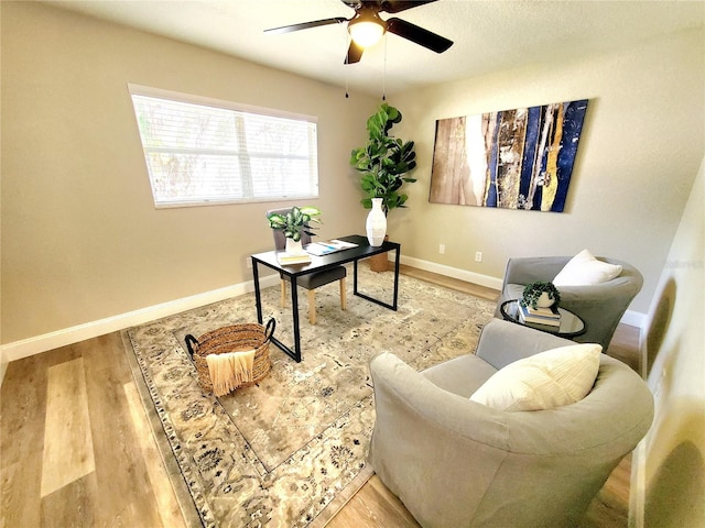 office area with wood finished floors, a ceiling fan, and baseboards