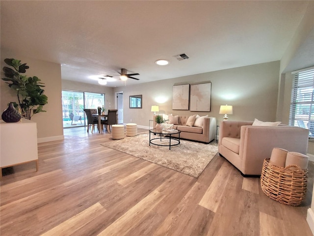 living room featuring visible vents, ceiling fan, light wood-style flooring, and baseboards