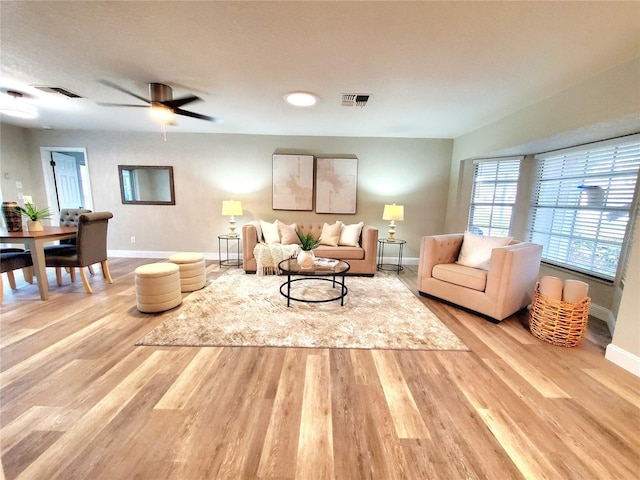 living room featuring a ceiling fan, baseboards, visible vents, and wood finished floors