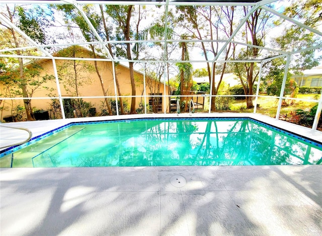 outdoor pool featuring glass enclosure and a patio