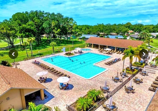 community pool with a lawn, a patio area, fence, and a hot tub