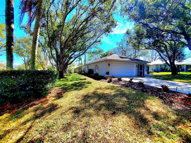 view of side of home featuring a garage, stucco siding, concrete driveway, and a yard