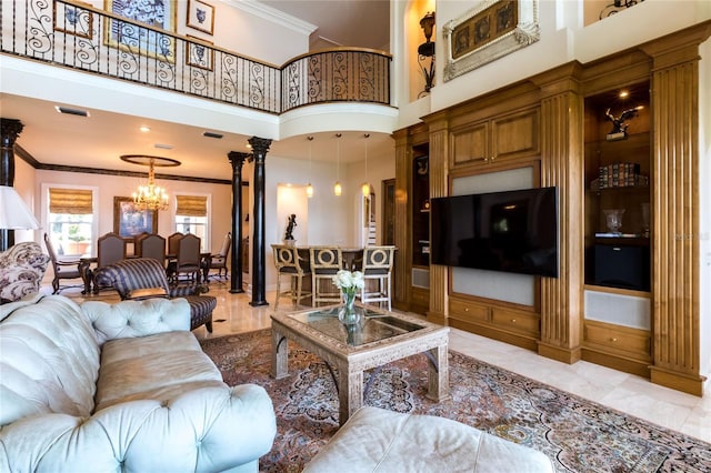 living room featuring decorative columns, a chandelier, a high ceiling, and ornamental molding