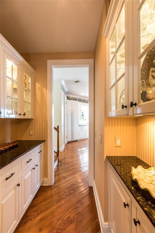 bar featuring a wealth of natural light, white cabinetry, dark stone counters, and dark hardwood / wood-style floors