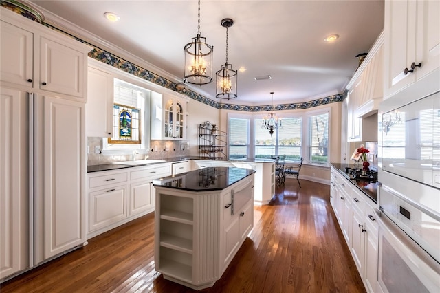 kitchen with white cabinetry, dark wood-type flooring, oven, decorative light fixtures, and a kitchen island