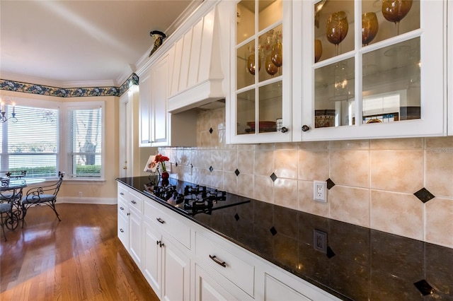 kitchen with decorative backsplash, white cabinets, black gas stovetop, and dark stone counters