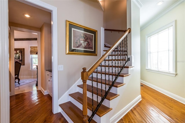 stairs featuring wood-type flooring and ornamental molding