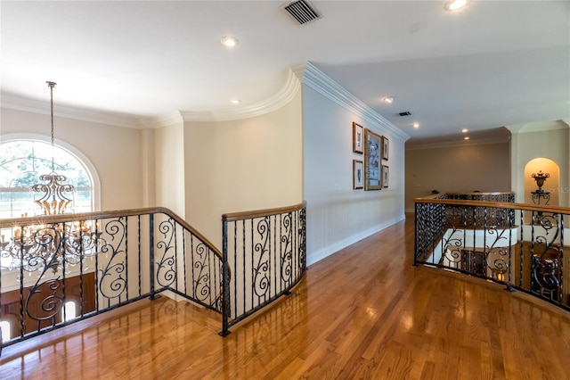 corridor featuring a notable chandelier, wood-type flooring, and crown molding