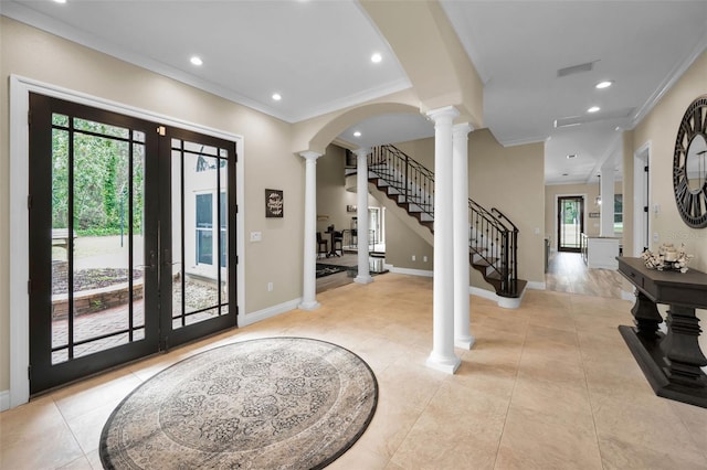 foyer entrance featuring ornate columns, crown molding, and french doors