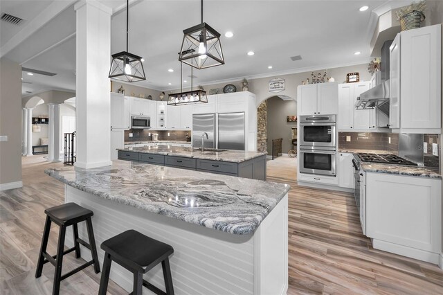 kitchen with white cabinets, decorative backsplash, pendant lighting, and high end appliances