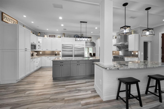 kitchen with white cabinets, premium appliances, a spacious island, and light stone countertops