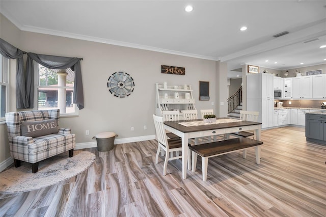 dining space featuring light hardwood / wood-style flooring and crown molding