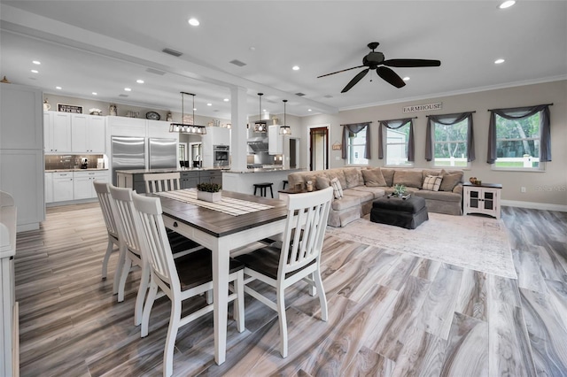 dining area featuring ceiling fan, light wood-type flooring, and ornamental molding