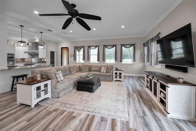 living room featuring light wood-type flooring, ceiling fan, and ornamental molding