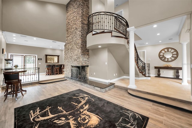 living room with decorative columns, a fireplace, a towering ceiling, and ornamental molding