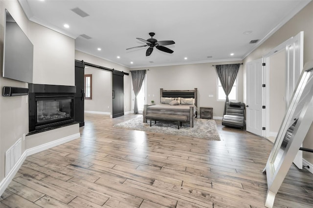 bedroom featuring a barn door, ceiling fan, crown molding, and light hardwood / wood-style flooring