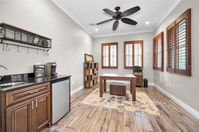 home office featuring crown molding, sink, ceiling fan, and light wood-type flooring