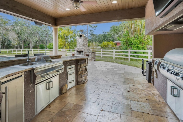 view of patio with an outdoor stone fireplace, area for grilling, and ceiling fan