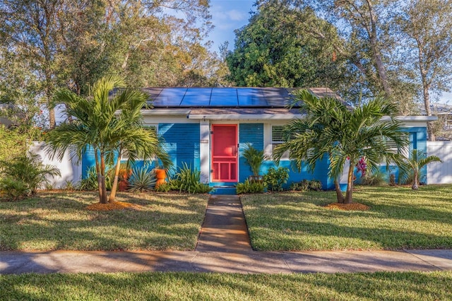 view of front of home with solar panels and a front yard