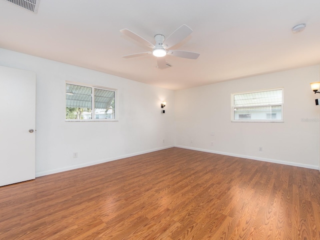 empty room with hardwood / wood-style floors, a healthy amount of sunlight, and ceiling fan