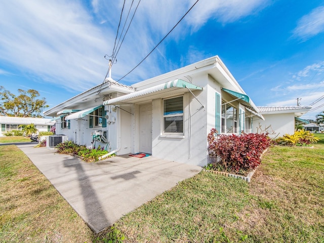 bungalow with central air condition unit and a front lawn