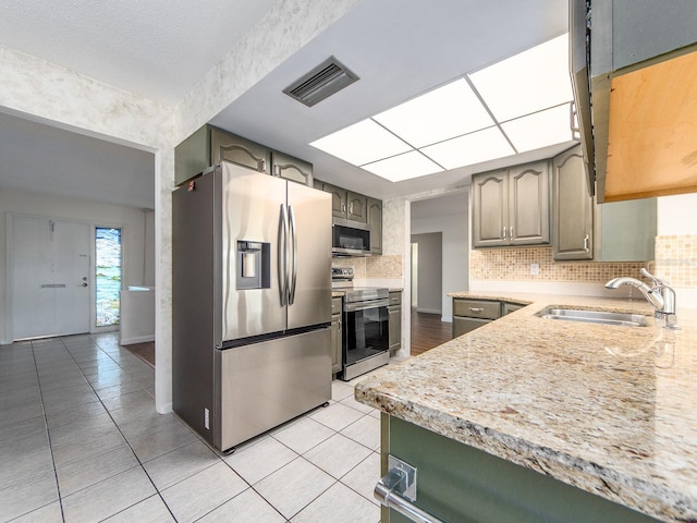 kitchen with light tile patterned flooring, appliances with stainless steel finishes, sink, and backsplash