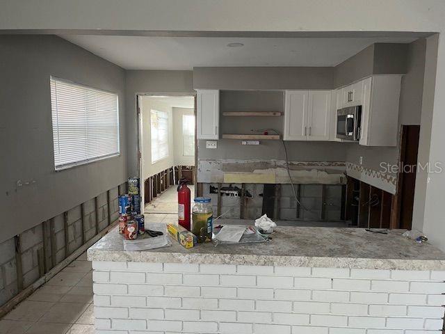 kitchen with white cabinets, light tile patterned flooring, and kitchen peninsula