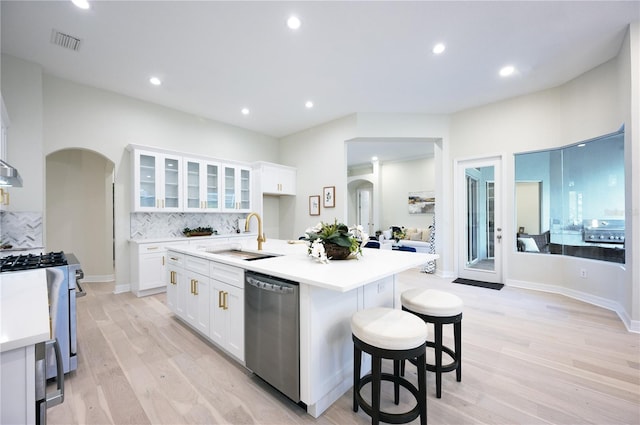 kitchen featuring white cabinetry, sink, stainless steel appliances, and a center island with sink