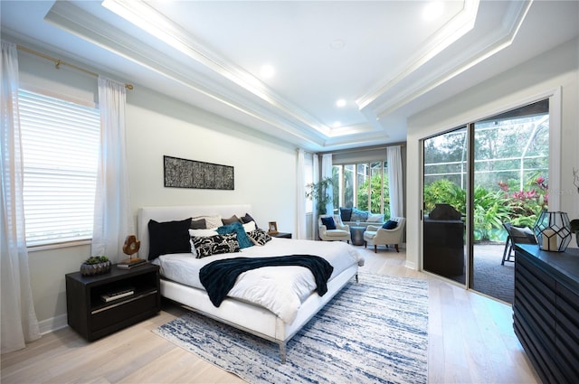 bedroom with a tray ceiling, crown molding, light wood-type flooring, and access to outside