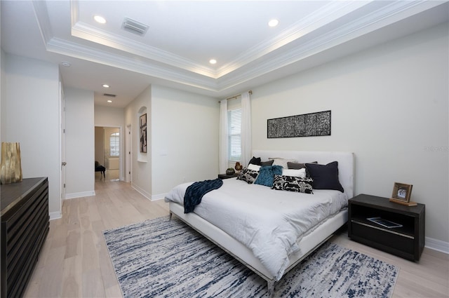 bedroom with hardwood / wood-style floors, a raised ceiling, and ornamental molding