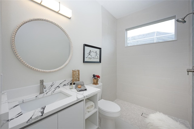 bathroom featuring vanity, toilet, and tiled shower