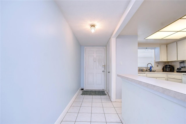 doorway with a textured ceiling, light tile patterned floors, and sink