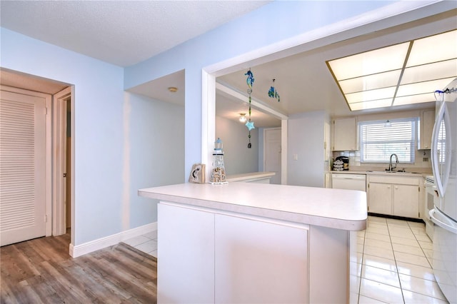 kitchen featuring white appliances, sink, decorative backsplash, a textured ceiling, and kitchen peninsula