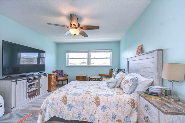 bedroom featuring ceiling fan, light hardwood / wood-style flooring, and a textured ceiling