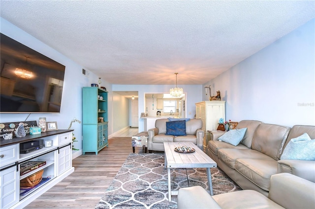 living room featuring hardwood / wood-style floors, a textured ceiling, and an inviting chandelier