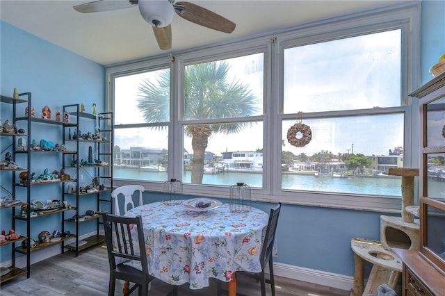 dining area with ceiling fan, hardwood / wood-style floors, and a water view