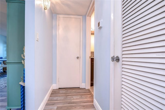 hallway with light hardwood / wood-style floors and a textured ceiling