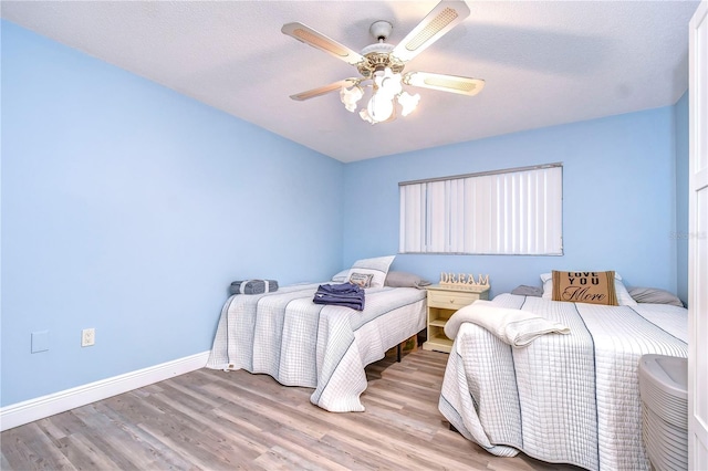 bedroom with ceiling fan, light wood-type flooring, and a textured ceiling