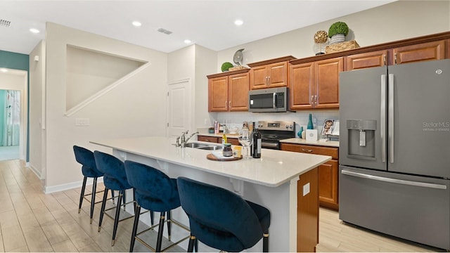 kitchen featuring sink, a kitchen bar, stainless steel appliances, and an island with sink