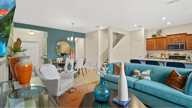 living room with light wood-type flooring and a notable chandelier