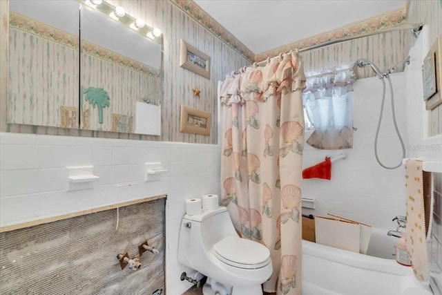 full bath featuring wallpapered walls, wainscoting, toilet, shower / bathtub combination with curtain, and tile walls