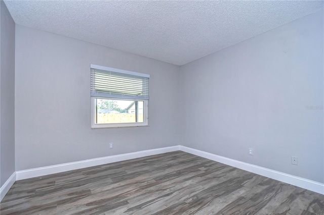 unfurnished room featuring dark wood-type flooring and a textured ceiling