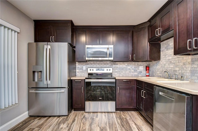 kitchen featuring dark brown cabinets, sink, stainless steel appliances, and light hardwood / wood-style flooring