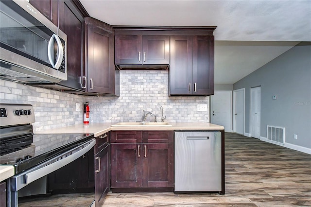 kitchen featuring backsplash, appliances with stainless steel finishes, sink, and hardwood / wood-style floors