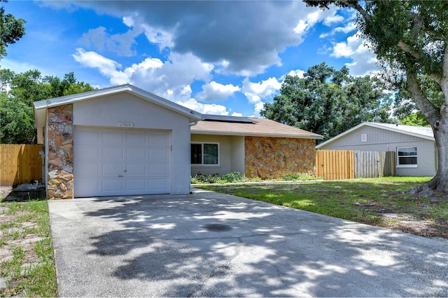 ranch-style house with a front lawn, a garage, and solar panels