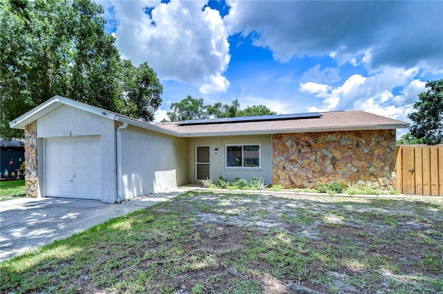 ranch-style house featuring a garage and solar panels